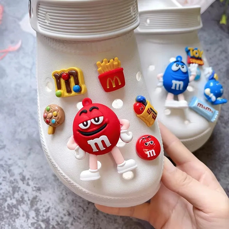 White shoe with colorful M&M's themed shoe charms on a gray surface.