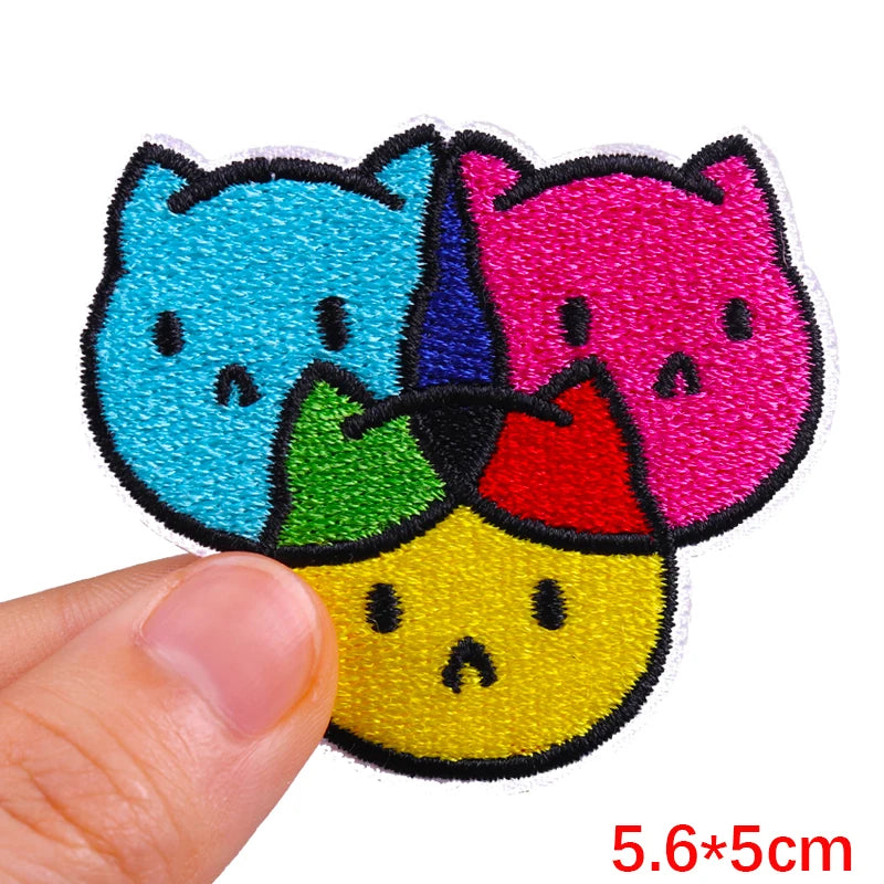 Colorful cat-shaped patch held by a hand with dimensions indicated.