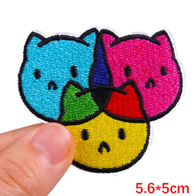 Colorful cat-shaped patch held by a hand with dimensions indicated.