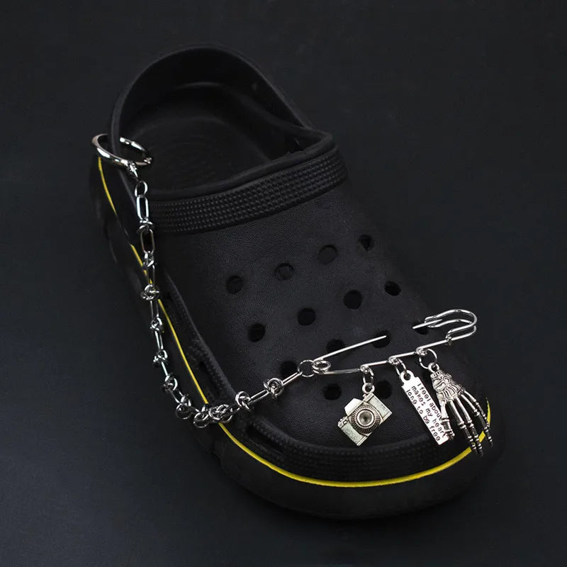 Black sandal with a silver chain featuring various charms on a dark background