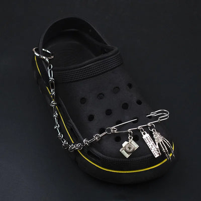 Black sandal with a silver chain featuring various charms on a dark background