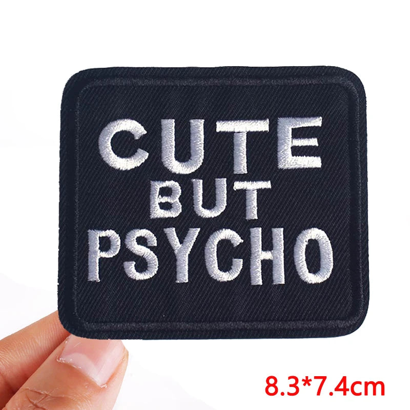 Black patch with 'Cute But Psycho' text held by a hand on a white background