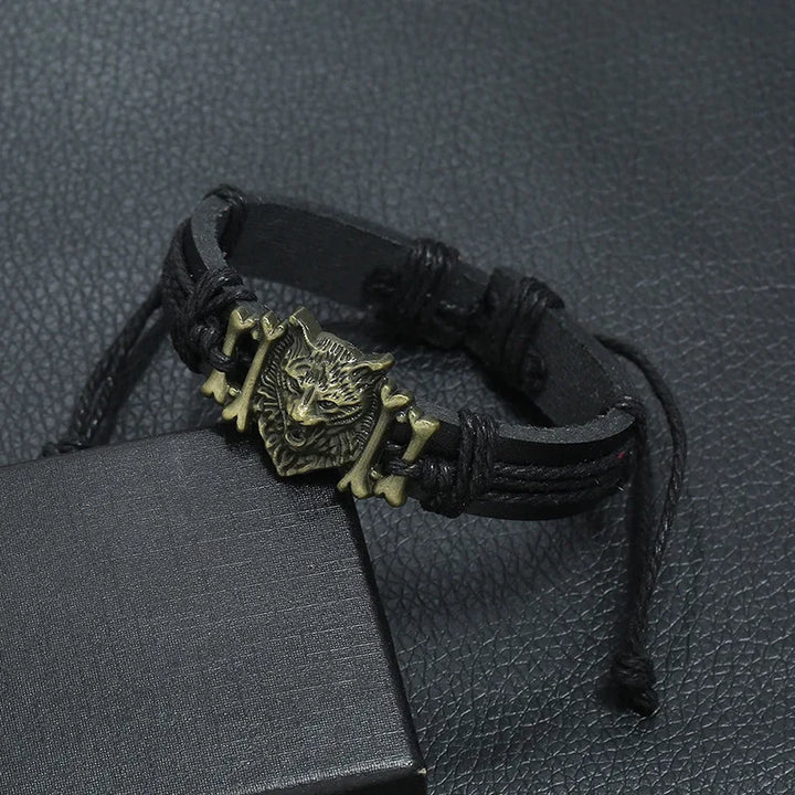Black leather bracelet with a wolf head charm on a textured black surface