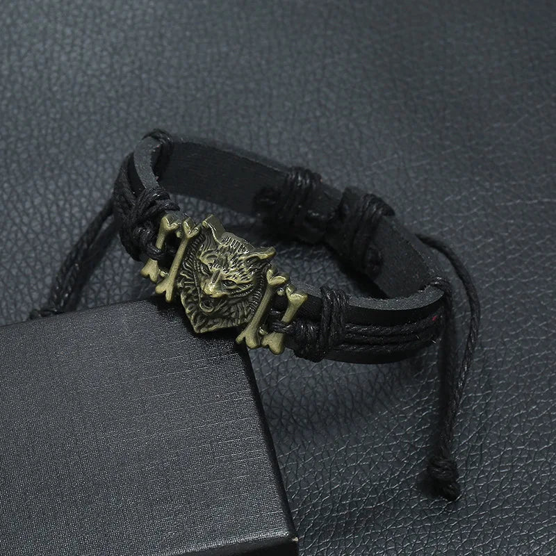 Black leather bracelet with a wolf head charm on a textured black surface