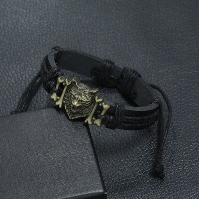 Black leather bracelet with a wolf head charm on a textured black surface