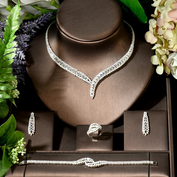 Jewelry set including necklace, bracelet, earrings, and ring on a brown stand with flowers around.