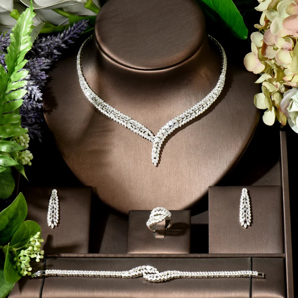 Jewelry set including necklace, bracelet, earrings, and ring on a brown stand with flowers around.