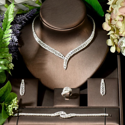 Jewelry set including necklace, bracelet, earrings, and ring on a brown stand with flowers around.