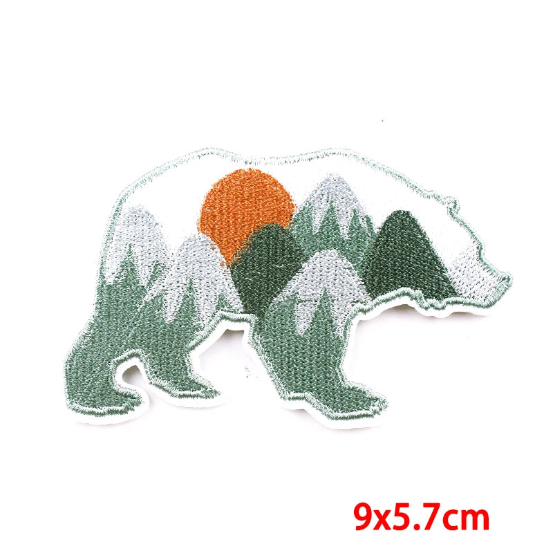 Embroidered patch of a bear with mountains and a sun on a white background