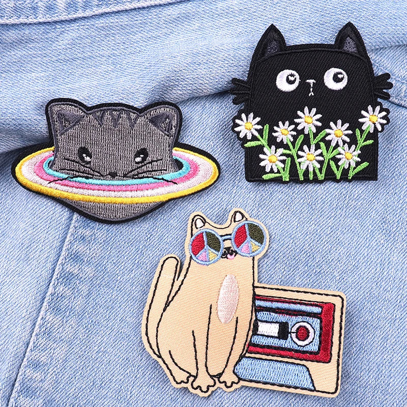 Three cat-themed patches on a denim background
