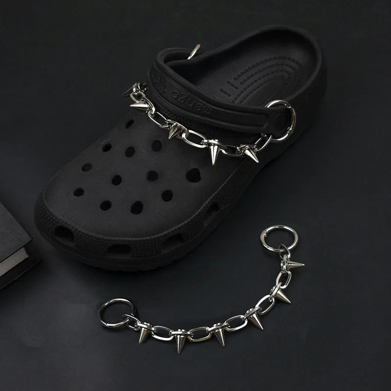 Black clog shoe with spiked chain on a dark background