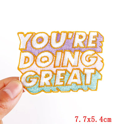 Embroidered patch with 'YOU'RE DOING GREAT' text held by a hand on a white background.