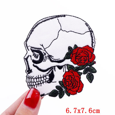 Skull patch with red roses held by a hand on a white background