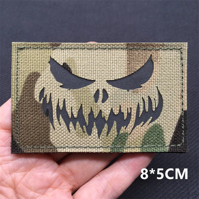 Camo patch with skull design held in hand against a dark background
