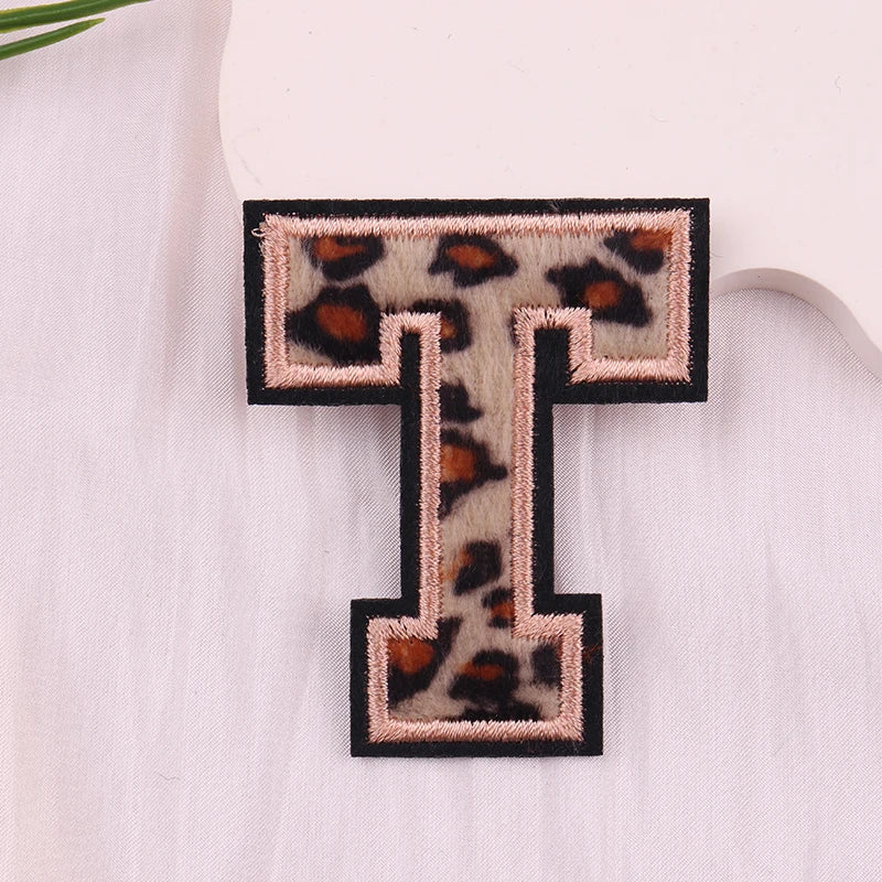 Leopard print letter 'T' patch on a white fabric background