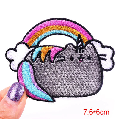 Embroidered patch of a cat with rainbow hair held by a hand on a white background