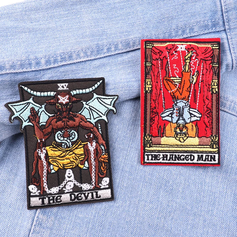 Two tarot card patches, 'The Devil' and 'The Hanged Man', on a denim background.