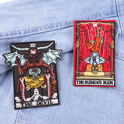 Two tarot card patches, 'The Devil' and 'The Hanged Man', on a denim background.