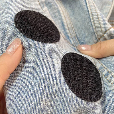 Black Velcro patches applied to a denim fabric, held by a hand.