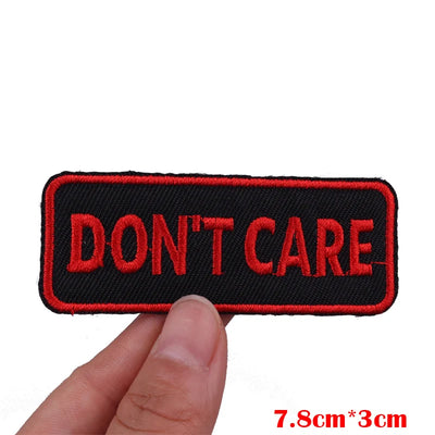 Embroidered patch with 'DON'T CARE' text held by a hand on a white background
