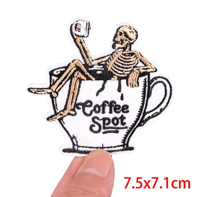 Skeleton sitting in a coffee cup with 'Coffee Spot' text, held by a hand.