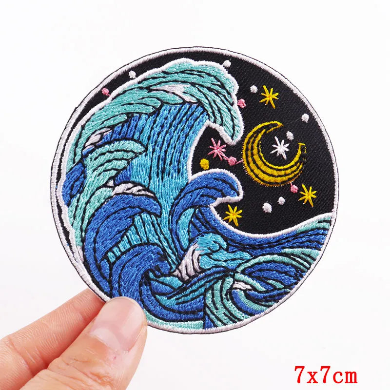 Embroidered patch with wave design held by a hand on a white background