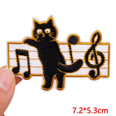 Embroidered patch of a black cat playing music on a white background