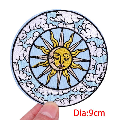 Circular patch with sun design held by a hand, against a white background