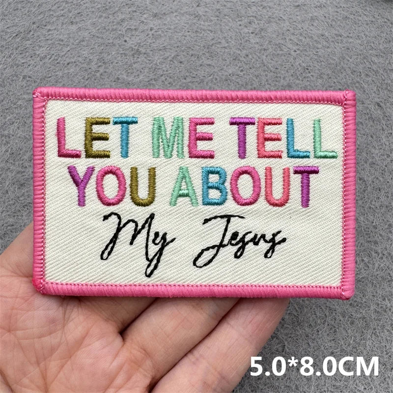 Embroidered patch with colorful text held in a hand on a gray background