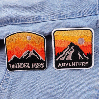 Two patches with mountain designs and text on a denim jacket.