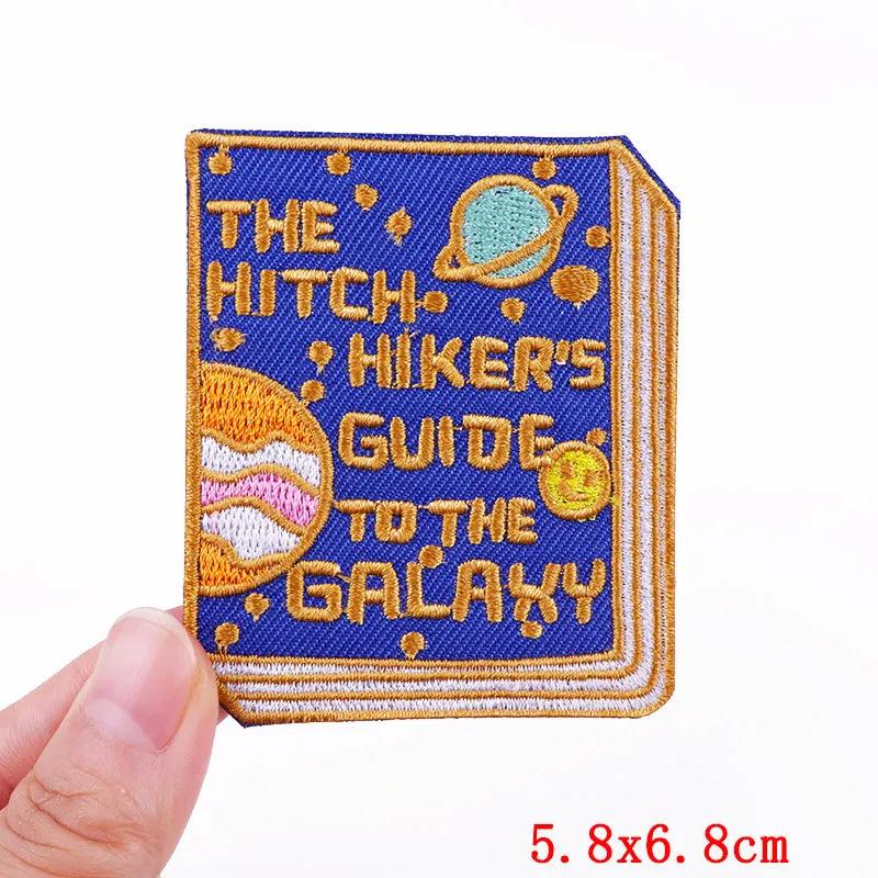 Embroidered patch of 'The Hitchhiker's Guide to the Galaxy' book held by a hand.