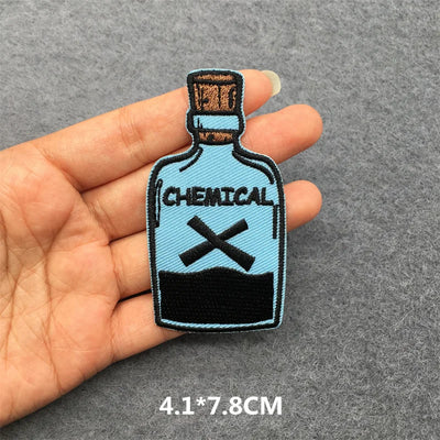 Patch of a bottle labeled 'Chemical' held between fingers on a gray background