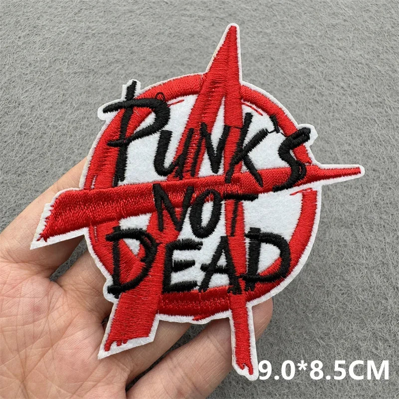 Punk's Not Dead patch held in a hand against a gray background