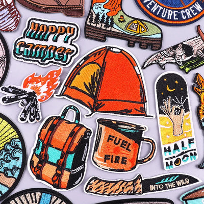 Collection of colorful camping-themed patches on a light gray background