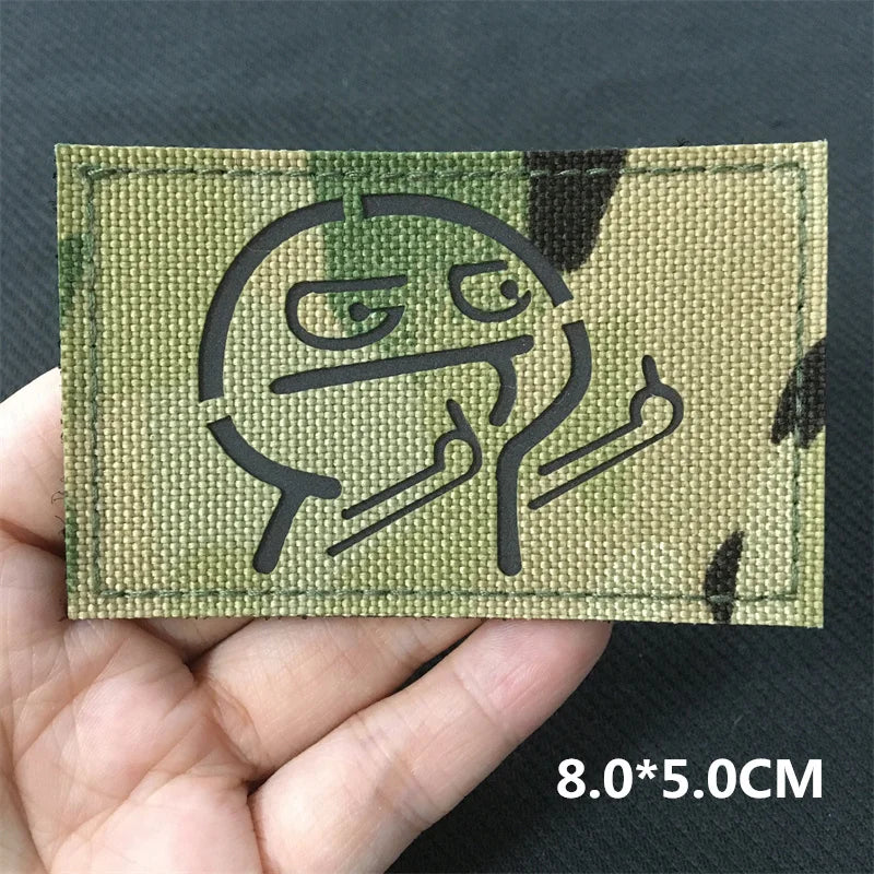 Green patch with a black outline design held in a hand against a dark background