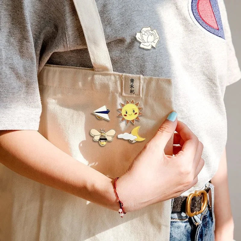 Person wearing various colorful pins on a beige apron with a neutral background