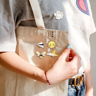 Person wearing various colorful pins on a beige apron with a neutral background