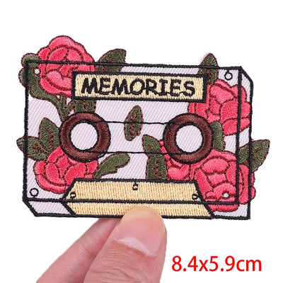Embroidered patch with cassette tape and roses design, labeled 'MEMORIES', held by a hand.