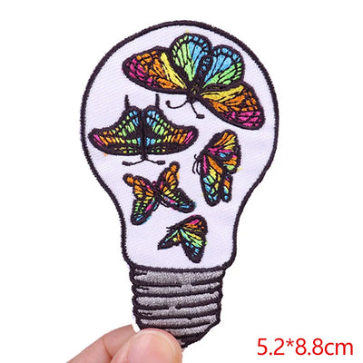 Light bulb-shaped patch with colorful butterflies held by a hand on a white background
