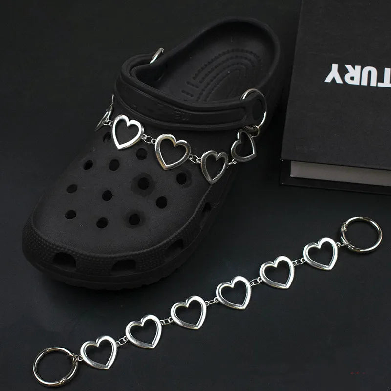 Black clog shoe with a silver heart-shaped charm on a dark background