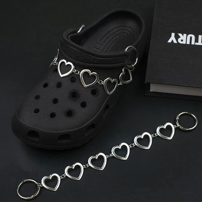 Black clog shoe with a silver heart-shaped charm on a dark background