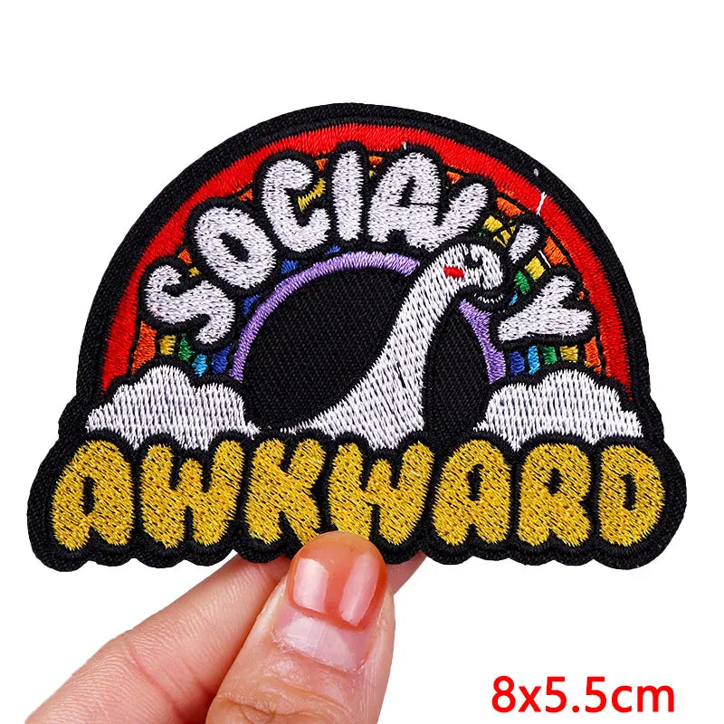 Patch with 'Socially Awkward' text held by a hand on a white background