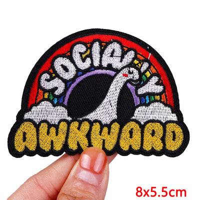 Patch with 'Socially Awkward' text held by a hand on a white background