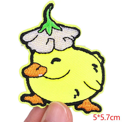 Embroidered patch of a yellow duck with a white flower on its head held by a hand.