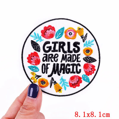 Circular patch with floral design and 'Girls are made of magic' text held by a hand.