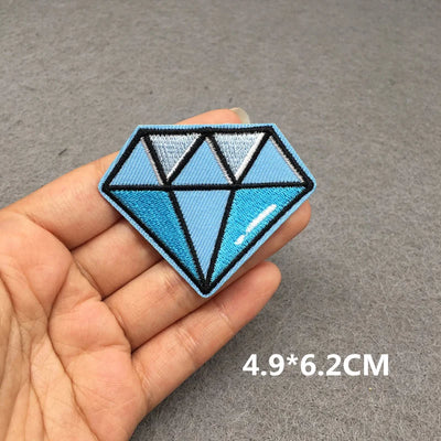 Blue geometric patch held in a hand with dimensions displayed on a gray background
