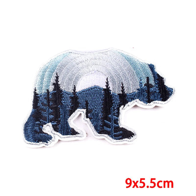 Embroidered patch of a forest scene with trees and mountains, size 9x5.5cm.