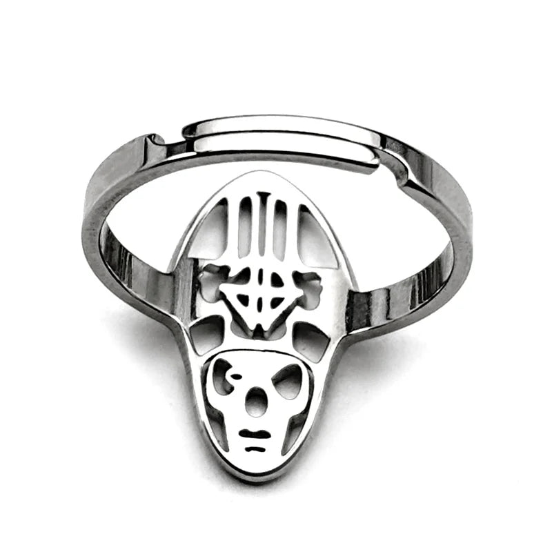 Silver metal ring with an intricately designed face featuring cut-outs and geometric patterns. The tone is modern and edgy, highlighting craftsmanship.