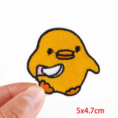 Yellow cartoon duck patch held by a hand with dimensions 5x4.7cm on a white background.