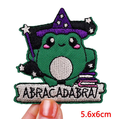 Green character with a purple hat and wand, holding a sign with 'Abracadabra', held by a hand.
